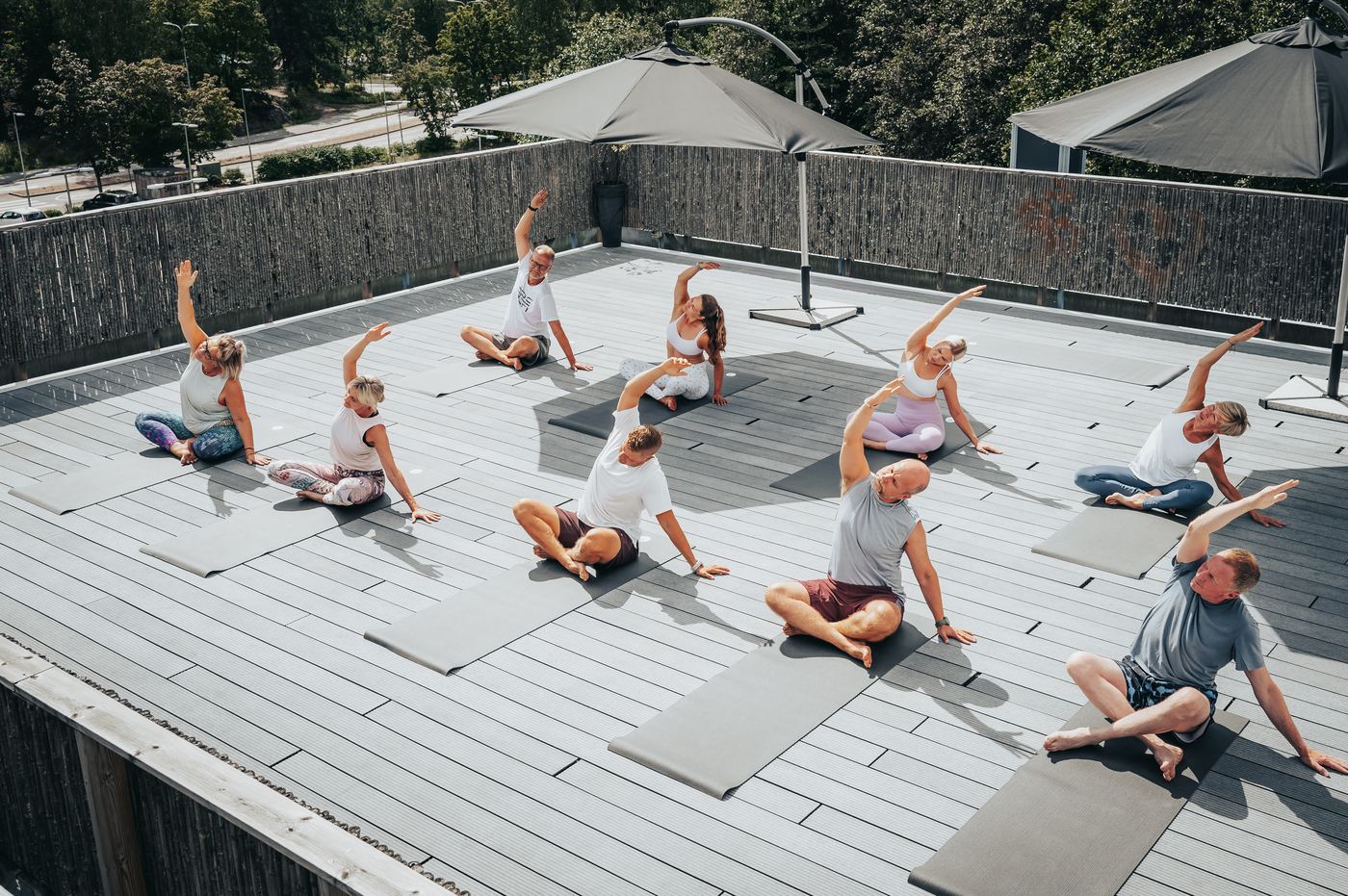 An outdoor yoga class on a sunny rooftop terrace